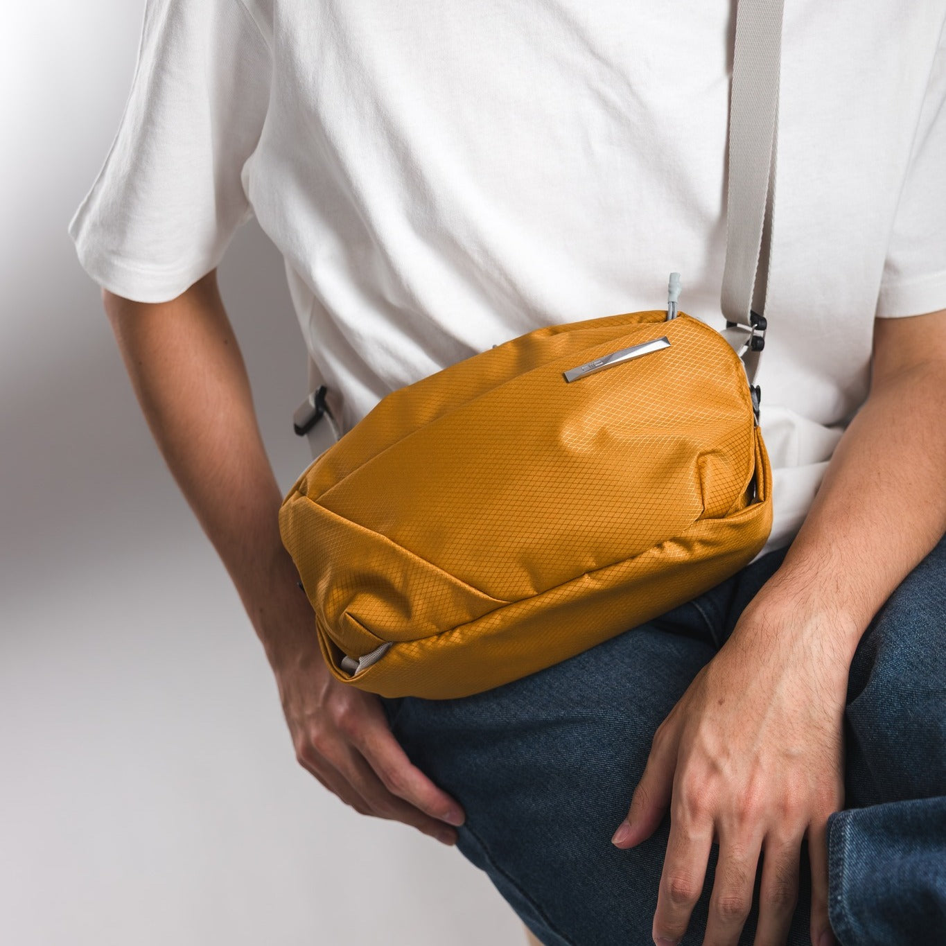 NIID NEO N1 Amber Orange sling bag on model, tactical everyday carry crossbody pack for urban professionals.