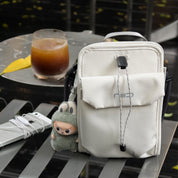 NIID NEO Nomad Pouch Pearly Gray Crossbody Bag Displayed on Outdoor Table