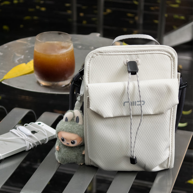 NIID NEO Nomad Pouch Pearly Gray Crossbody Bag Displayed on Outdoor Table