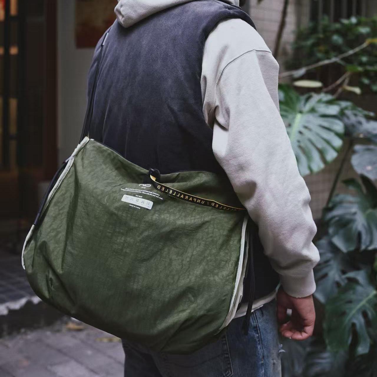 NIID S7 Statement Reversible Tote Bag in Olive and Khaki - Rear View Lifestyle Wearing Shot with Green Plants Background for Daily Urban Travel