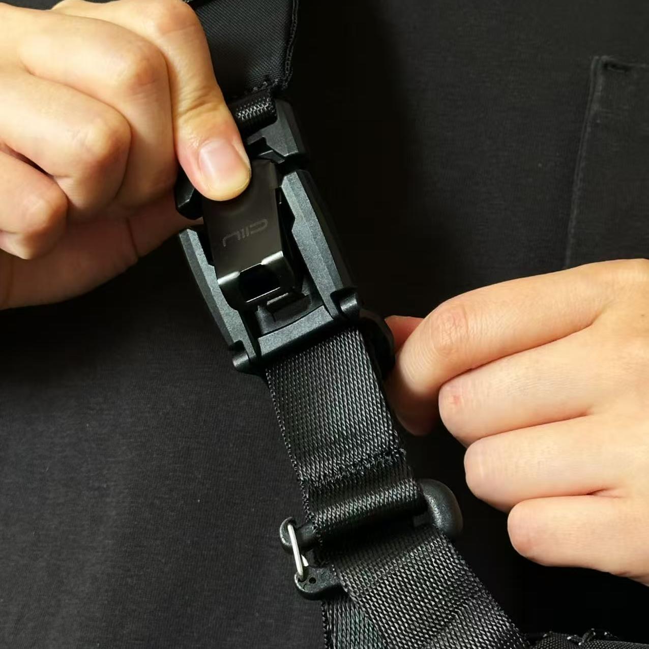 Hands demonstrating NIID F5 sling bag quick‑release buckle operation, close‑up of black nylon strap and magnetic buckle detail