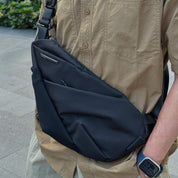 NIID FINO V Ultra‑slim Tech Sling Black Noir crossbody on person in tan shirt, outdoor city sidewalk casual daily carry shot