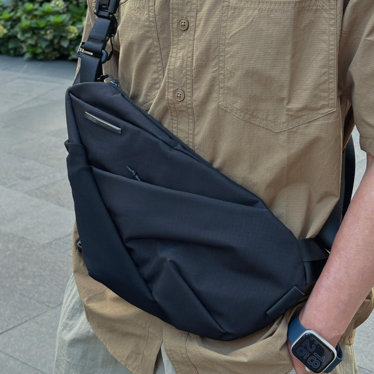 NIID FINO V Ultra‑slim Tech Sling Black Noir crossbody on person in tan shirt, outdoor city sidewalk casual daily carry shot