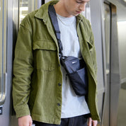 Man at subway station wearing NIID FINO V Ultra‑slim Tech Sling Gray Shadow Grid crossbody sling bag, casual urban commute lifestyle