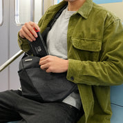 Man on train taking Nintendo Switch out of NIID FINO V Ultra‑slim Tech Sling Gray Shadow Grid crossbody sling bag, tech carry commute scene