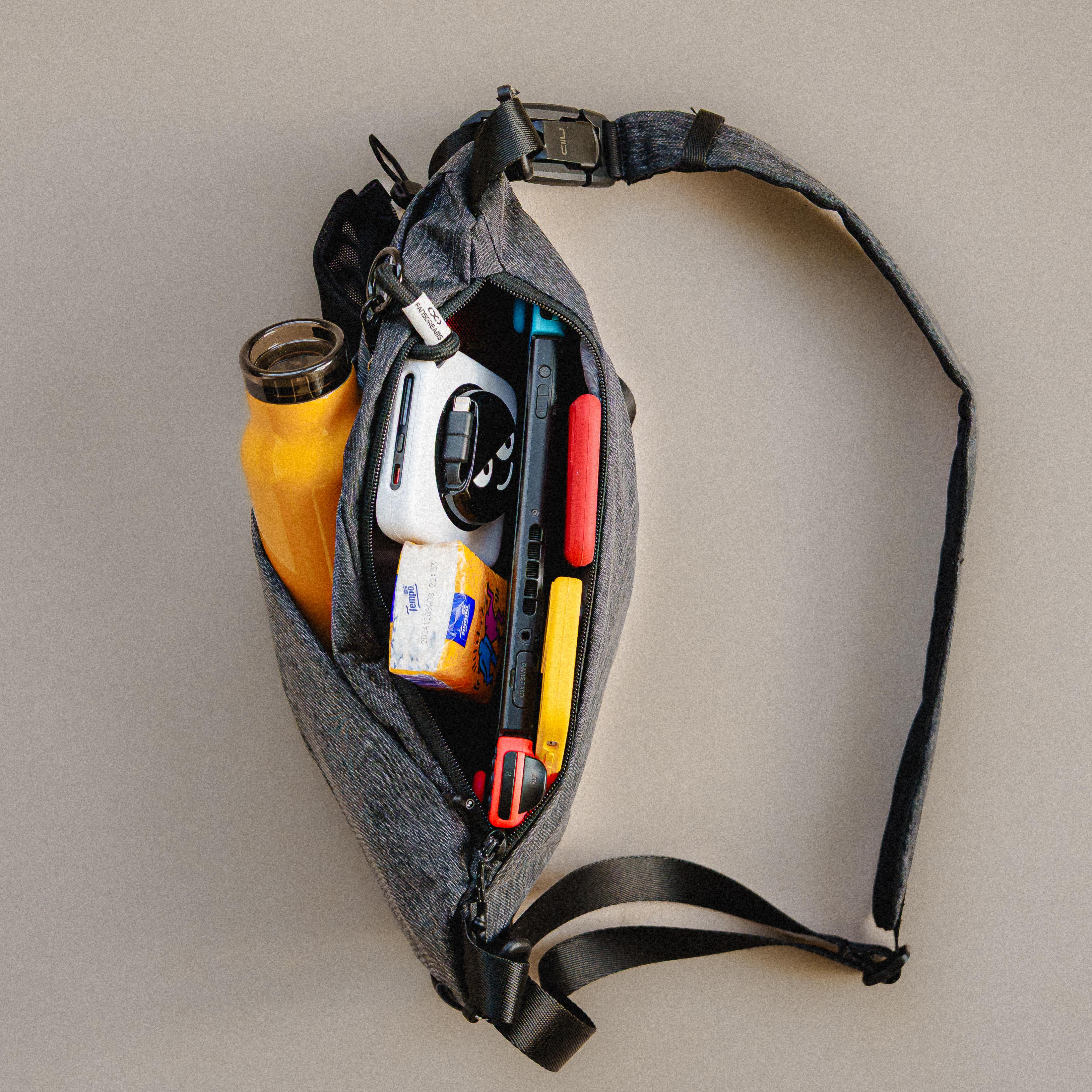 Top‑down shot of NIID FINO V Ultra‑slim Tech Sling Gray Shadow Grid, open bag displaying interior storage with daily tech and travel essentials