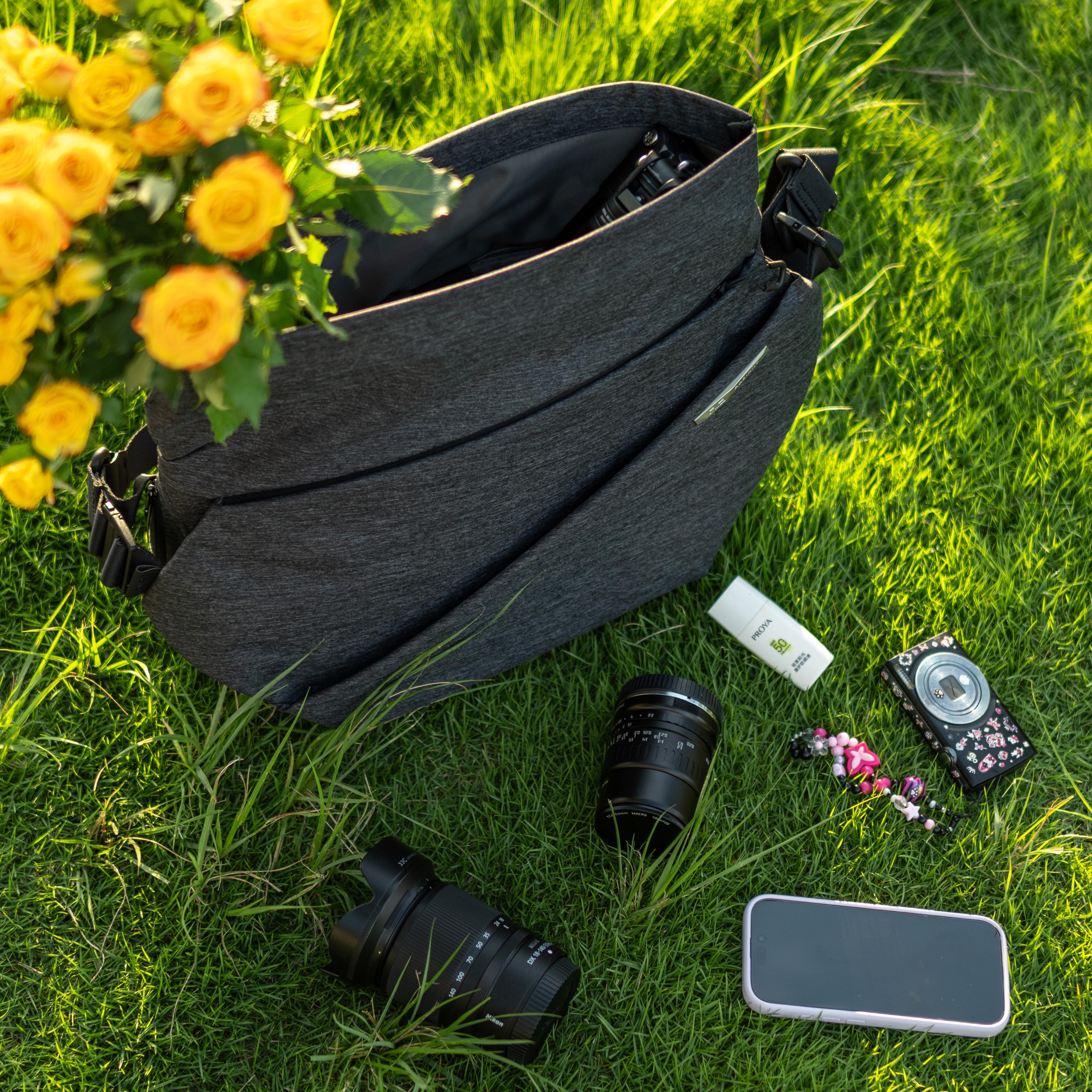 NIID R1 Radiant Mega gray messenger sling bag outdoor grass flat‑lay, matched with camera lenses, smartphone and yellow rose bouquet, photographer lifestyle scene